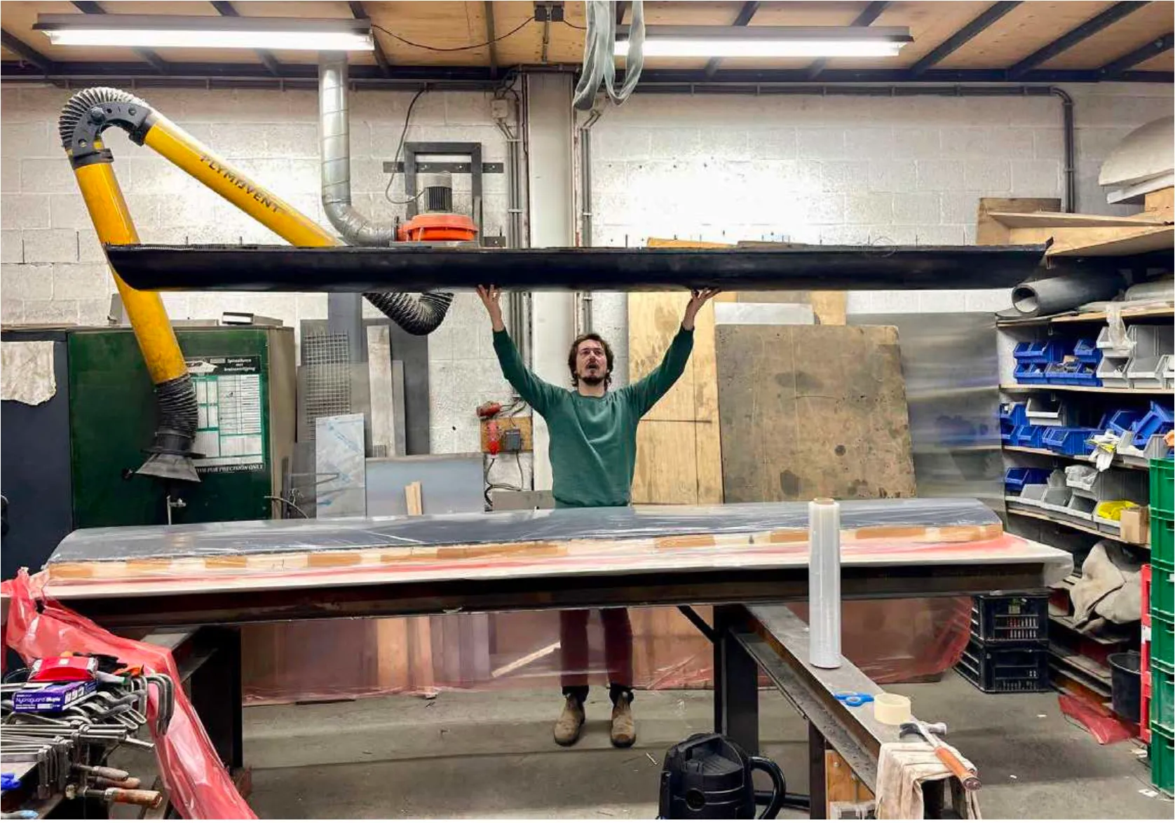 a person holding up a long black panel in a workshop